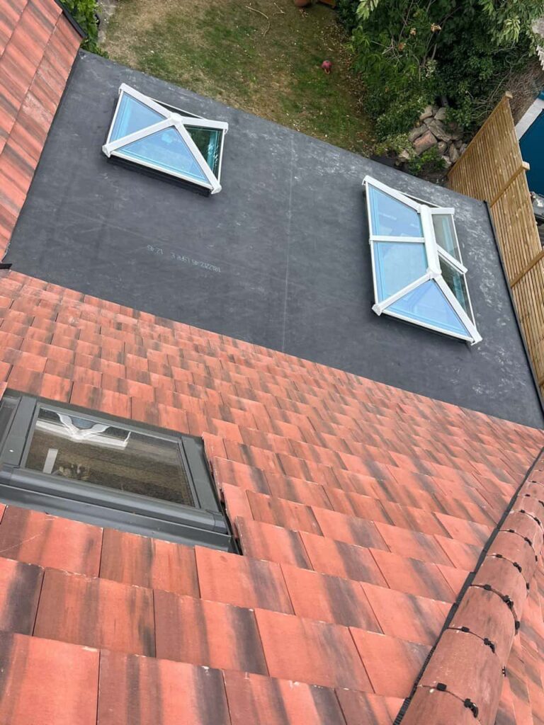 This is a photo taken from the roof ridge looking down a tiled pitched roof on to a flat roof. Works carried out by LJ Roofing Cirencester
